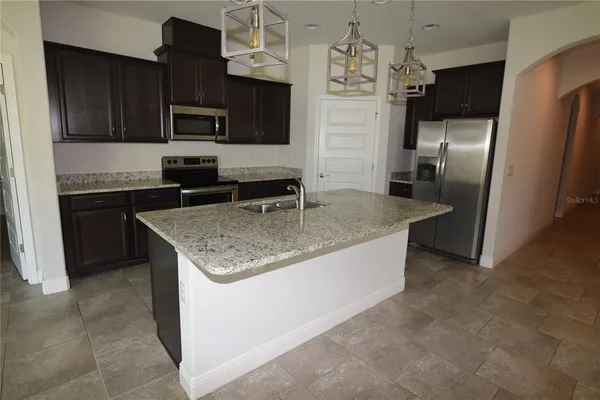 a kitchen with stainless steel appliances granite countertop a sink dishwasher a refrigerator and a stove