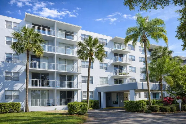 a front view of multi story residential apartment building with a yard and potted plants