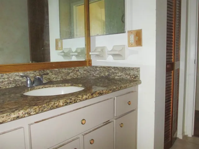 a bathroom with a granite countertop sink and a mirror