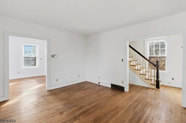 a view of an empty room with wooden floor and stairs