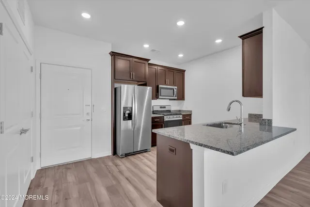 a kitchen with kitchen island a counter top space stainless steel appliances and wooden floor