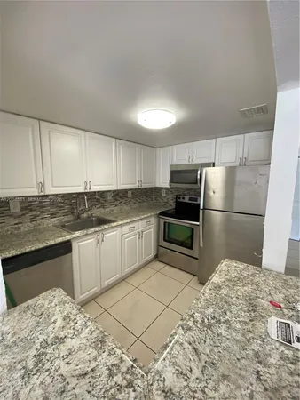 a kitchen with granite countertop a refrigerator and a stove top oven