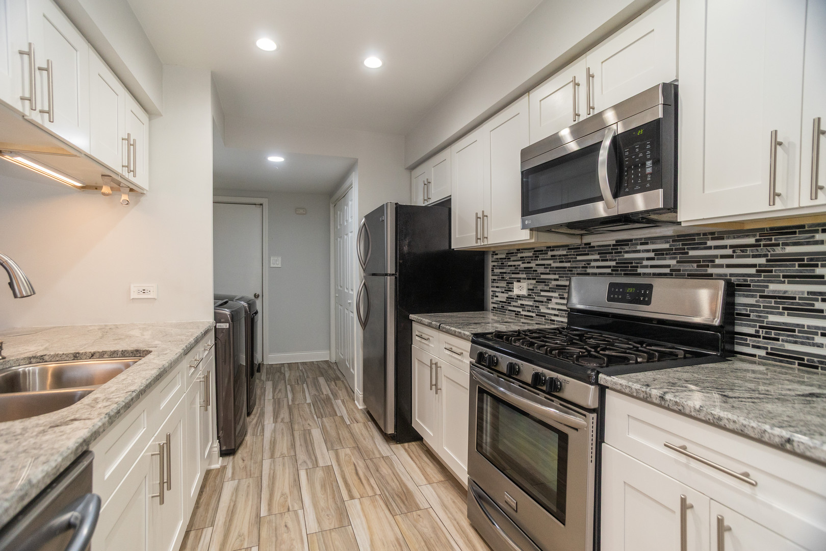 14451 South Ravinia Avenue, Unit 1 Orland Park, IL 60462 - Photo 9 of 22 a kitchen with stainless steel appliances kitchen island granite countertop a stove a sink and a microwave
