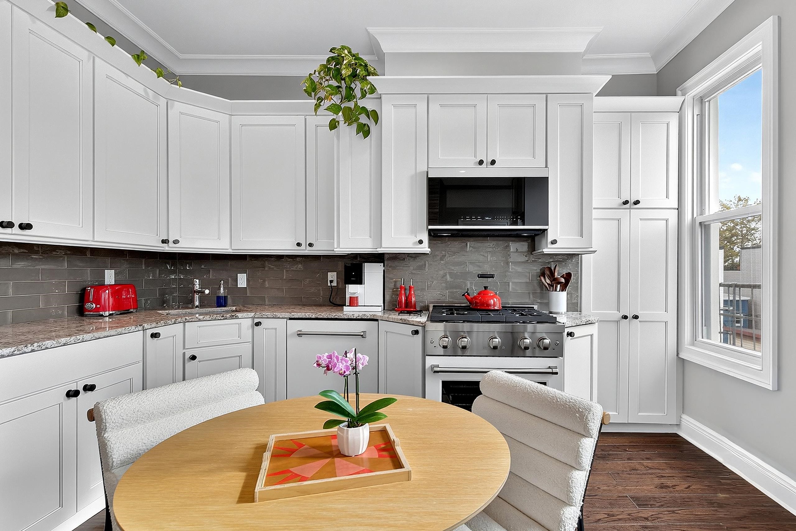 a kitchen with stainless steel appliances kitchen island granite countertop a refrigerator a stove a sink dishwasher and white cabinets with wooden floor