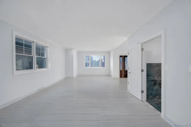 a view of an empty room with kitchen and window