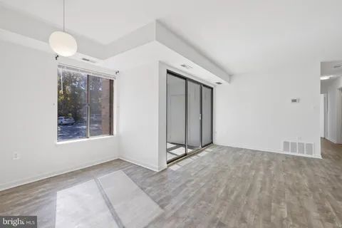a view of an empty room with window and wooden floor