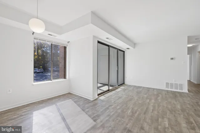 a view of an empty room with window and wooden floor
