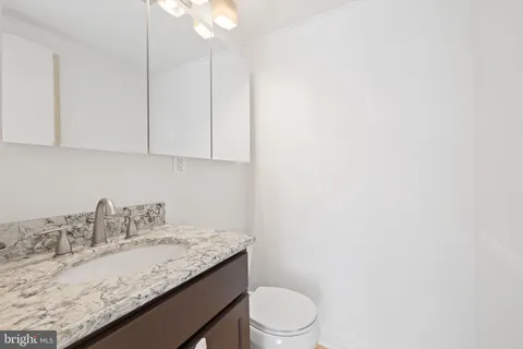 a bathroom with a granite countertop sink a toilet and vanity