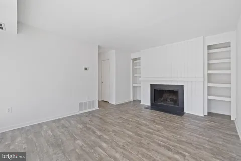 a view of empty room with wooden floor and fireplace