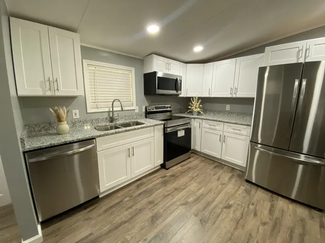 a kitchen with white cabinets stainless steel appliances and a sink