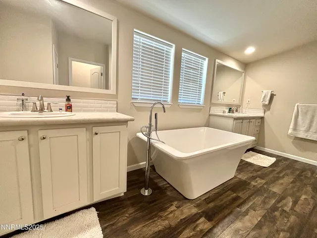 a spacious bathroom with a tub a sink and a mirror