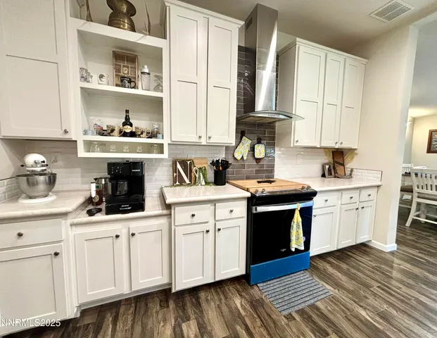 a kitchen with a sink dishwasher stove and white cabinets with wooden floor
