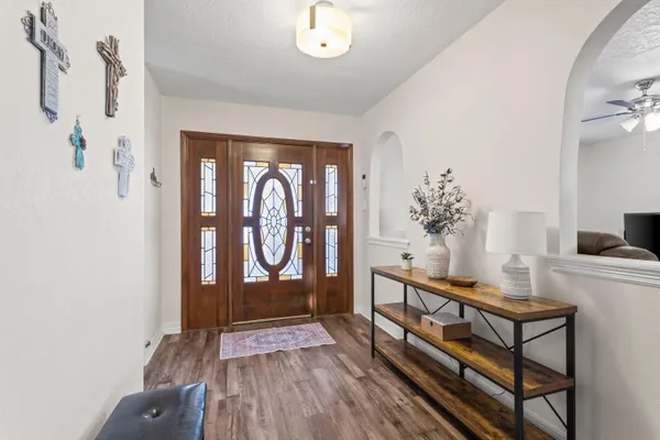 a view of a hallway to a livingroom with wooden floor and furniture