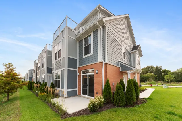 a view of a white house with a big yard and potted plants