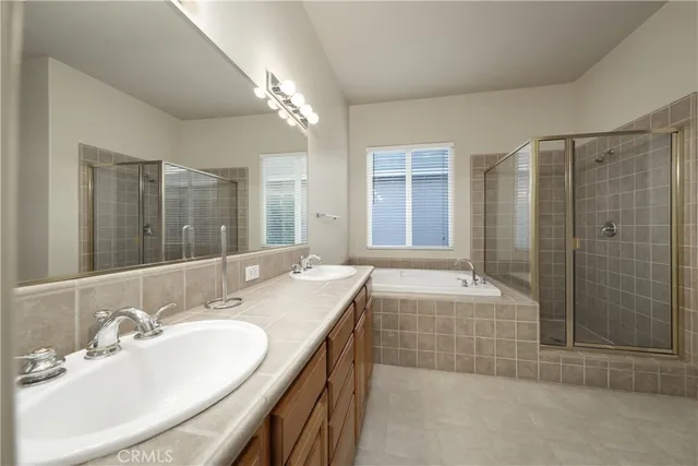 a bathroom with a granite countertop sink a mirror a bathtub and shower