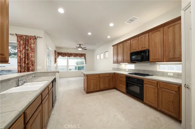 a large kitchen with stainless steel appliances granite countertop a sink counter space cabinets and a stove