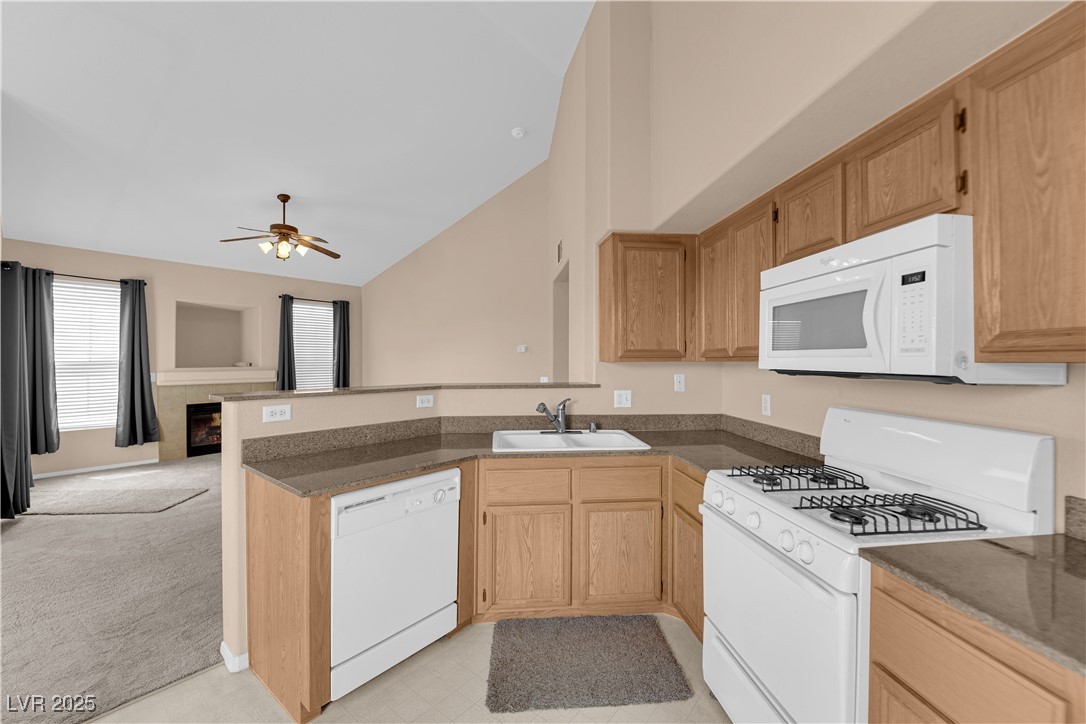 10550 West Alexander Road, Unit 2233 Las Vegas, NV 89129 - Photo 35 of 35 Kitchen featuring a sink, a peninsula, white appliances, vaulted ceiling, and open floor plan