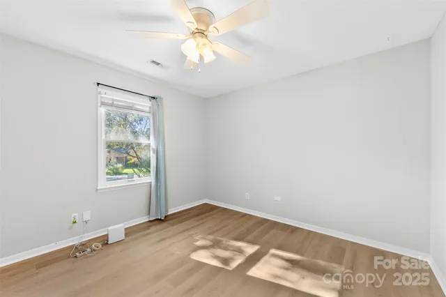 an empty room with a window and a fan