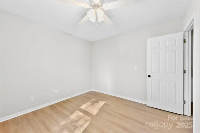 a view of a room with a ceiling fan and wooden floor