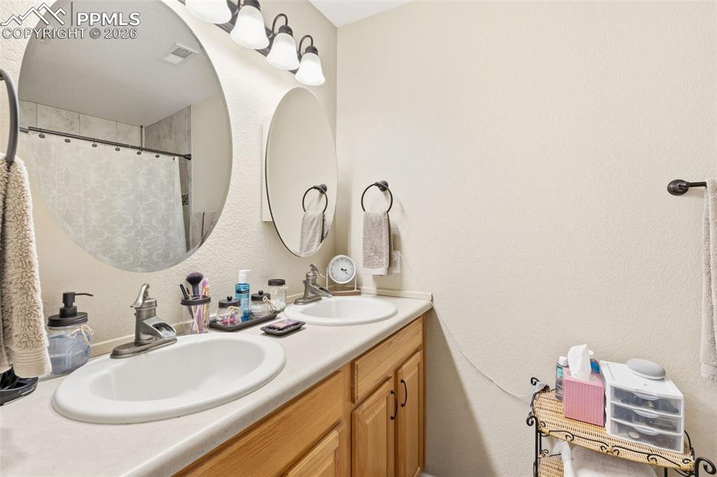 3519 Grey Owl Point Colorado Springs, CO 80916 - Photo 19 of 29 Full bathroom with a textured wall, double vanity, and a shower with curtain