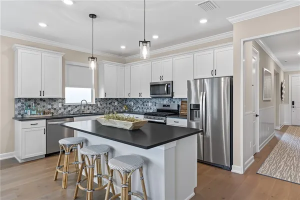a kitchen with stainless steel appliances granite countertop a refrigerator a sink a stove a dining table and chairs