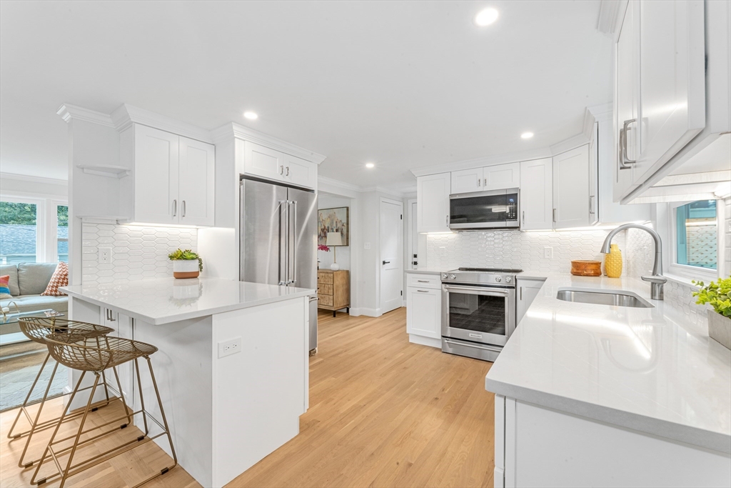 26 Crehore Road Boston, MA 02467 - Photo 9 of 33 a kitchen with a refrigerator a stove top oven a sink dishwasher and white cabinets with wooden floor
