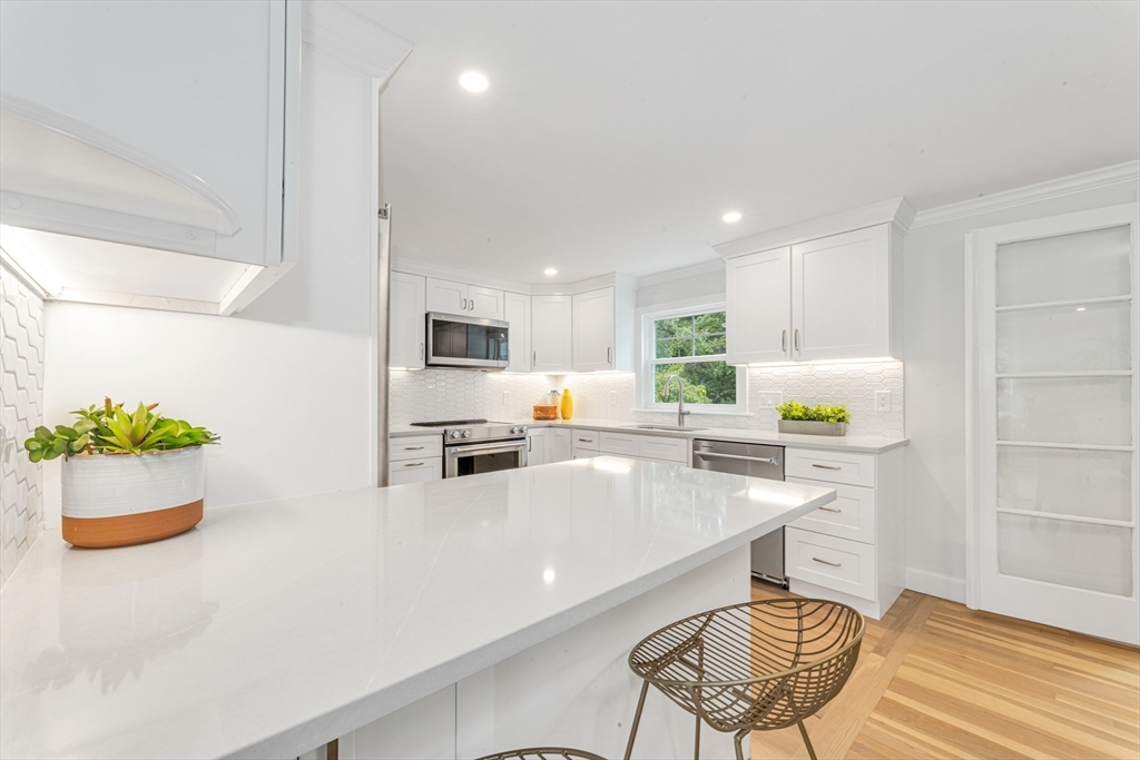 26 Crehore Road Boston, MA 02467 - Photo 10 of 33 a kitchen with stainless steel appliances kitchen island granite countertop a refrigerator a stove a sink dishwasher and white cabinets with wooden floor