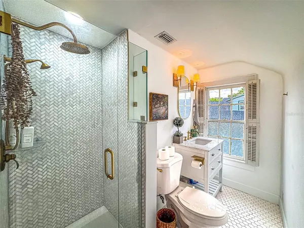 a bathroom with a sink a toilet a shower and a mirror