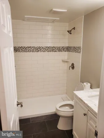 a bathroom with a granite countertop bathtub shower sink vanity and toilet