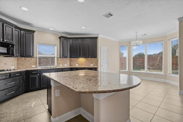 a kitchen with kitchen island granite countertop a sink a counter top space appliances and cabinets