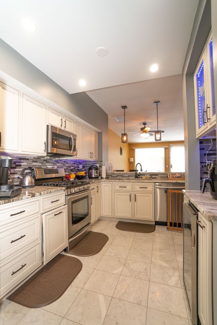8233 Ripple Ridge, Unit 8233 Darien, IL 60561 - Photo 3 of 18 a kitchen with stainless steel appliances granite countertop a stove a sink and white cabinets