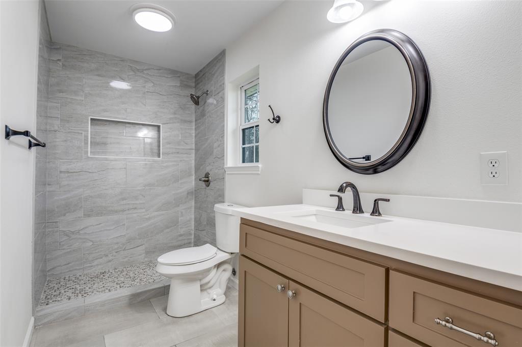 1055 Wright Street Terrell, TX 75160 - Photo 16 of 20 a bathroom with a toilet a sink a mirror and a shower