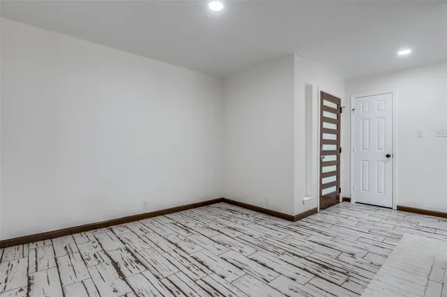 a view of an empty room with wooden floor and closet