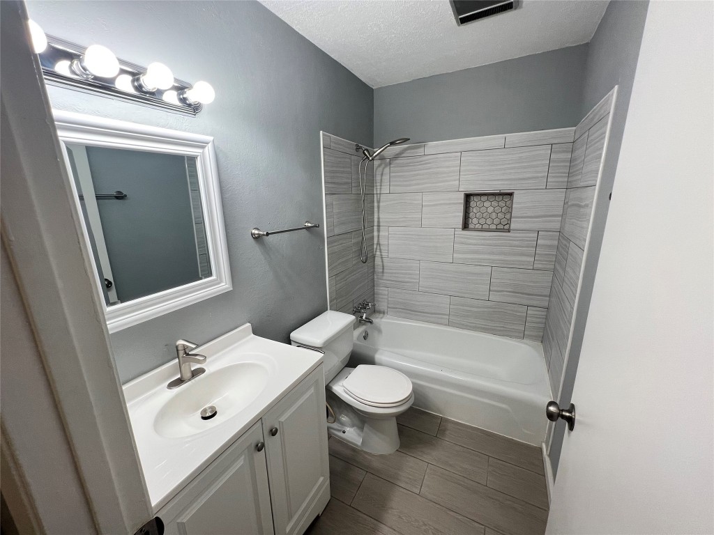 5808 Wellington Drive, Unit 4 Austin, TX 78723 - Photo 10 of 12 a bathroom with a bathtub shower sink mirror vanity and toilet