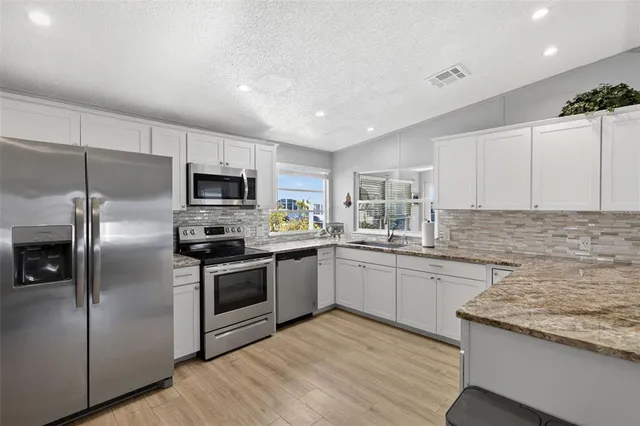 a kitchen with a sink dishwasher stove and cabinets