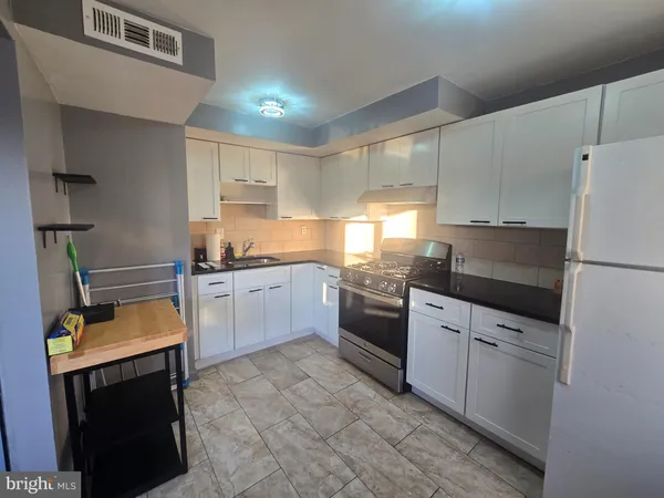a kitchen with granite countertop a refrigerator stove top oven and sink