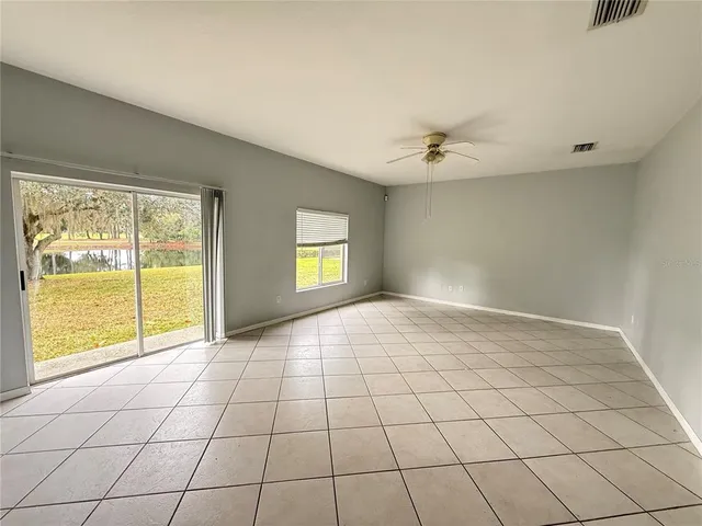 an empty room with wooden floor chandelier fan and windows