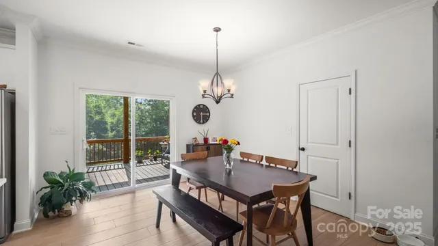 a dining room with wooden floor a chandelier a glass table and chairs