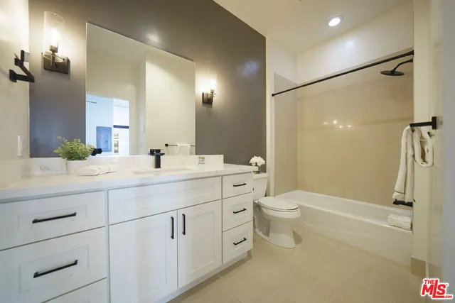 a bathroom with a double vanity sink toilet mirror and shower