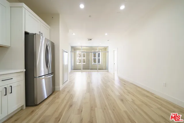 a view of a kitchen with a refrigerator and wooden floor