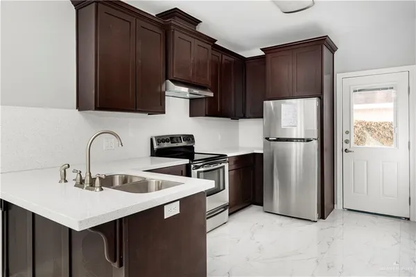 a kitchen with stainless steel appliances a refrigerator a sink a stove and cabinets