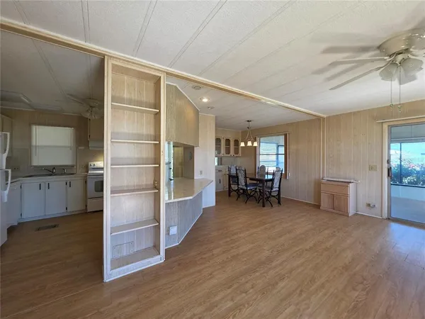 a view of empty room with wooden floor and fan
