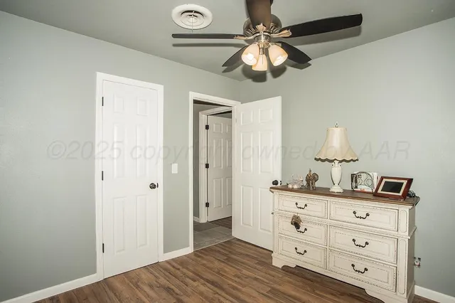 a view of room with cabinet ceiling fan and wooden floor