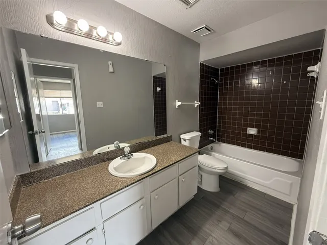 a bathroom with a granite countertop sink a toilet a mirror and shower
