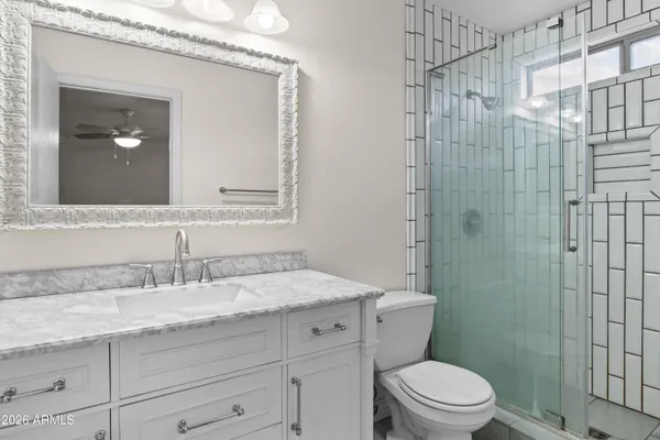 a bathroom with a granite countertop sink a toilet and shower