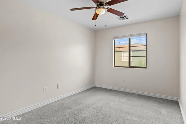 an empty room with chandelier fan and windows