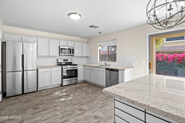 a kitchen with stainless steel appliances granite countertop a stove a sink dishwasher a refrigerator and a oven with wooden floor