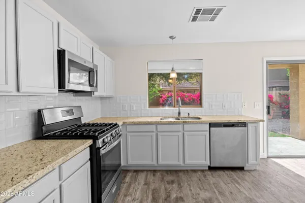 a kitchen with stainless steel appliances granite countertop a stove a sink and a microwave