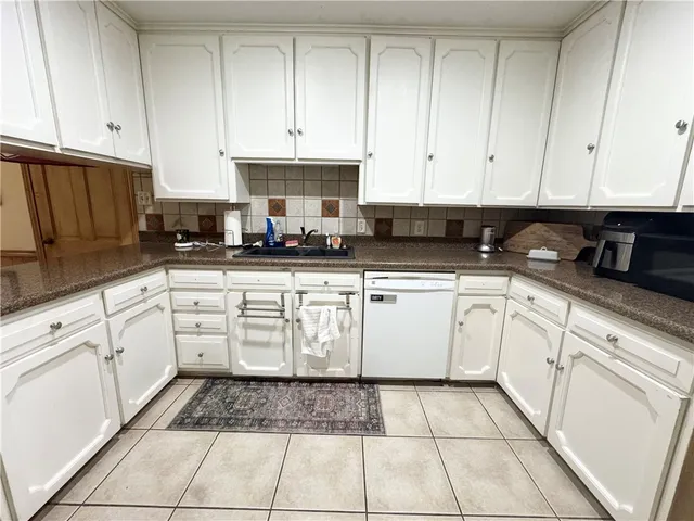 a white kitchen with granite countertop white cabinets