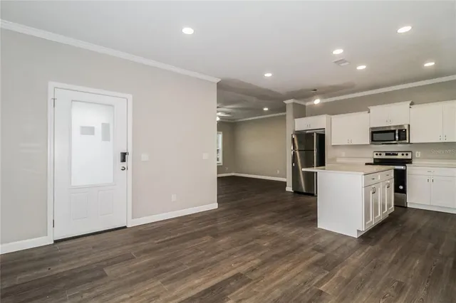 a view of kitchen with microwave a refrigerator and white cabinets